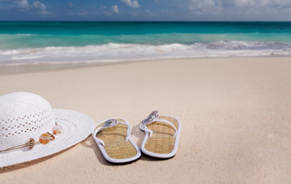 Female Flip-Flop and Hat on a Beach - Best Things to Pack for a Luxury Cruise